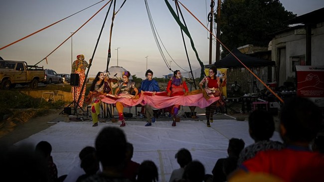 People watch a performance by members of the TET Center for Artistic Creation during the 6th Social Festival of Performing Arts in Playa Verde, Catia La Mar, La Guaira state, Venezuela, on October 18, 2026. The TET Center for Artistic Creation perfor
