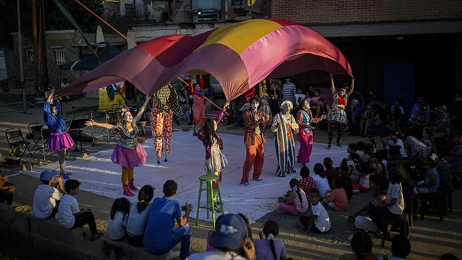 People watch a performance by members of the TET Center for Artistic Creation during the 6th Social Festival of Performing Arts in Playa Verde, Catia La Mar, La Guaira state, Venezuela, on October 18, 2026. The TET Center for Artistic Creation perfor