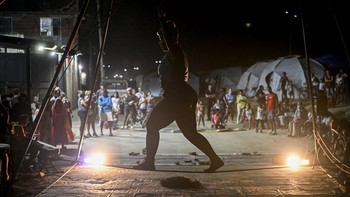 People watch a performance by members of the TET Center for Artistic Creation during the 6th Social Festival of Performing Arts in Playa Verde, Catia La Mar, La Guaira state, Venezuela, on October 18, 2026. The TET Center for Artistic Creation perfor