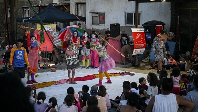 People watch a performance by members of the TET Center for Artistic Creation during the 6th Social Festival of Performing Arts in Playa Verde, Catia La Mar, La Guaira state, Venezuela, on October 18, 2026. The TET Center for Artistic Creation perfor