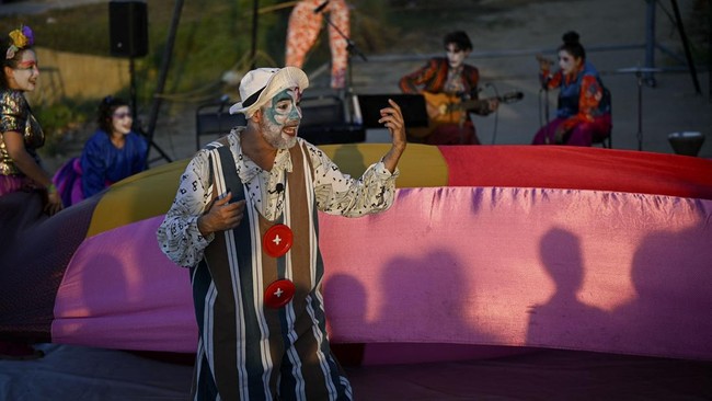 People watch a performance by members of the TET Center for Artistic Creation during the 6th Social Festival of Performing Arts in Playa Verde, Catia La Mar, La Guaira state, Venezuela, on October 18, 2026. The TET Center for Artistic Creation perfor