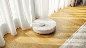 Robot vacuum cleaner operating on a light wooden floor, promoting smart home technology and automated housework