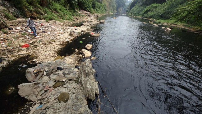 Warga melihat kondisi Sungai CIleungsi berwarna hitam diduga tercemar limbah di Wanaherang, Gunung Putri, Kabupaten Bogor, Jawa Barat, Selasa (20/10/2026). Dinas Lingkungan Hidup (DLH) menyebut bahwa penyebab kembali menghitamnya aliran Sungai Cileun