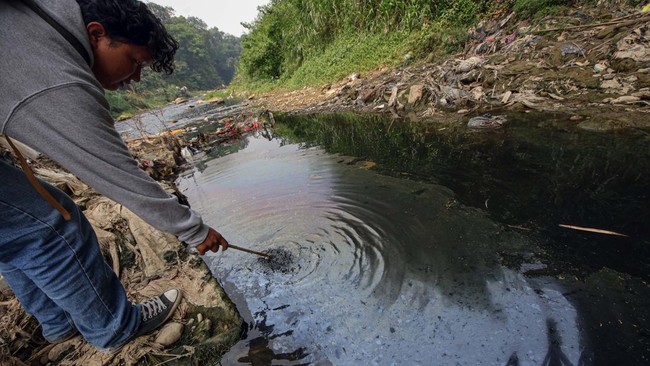 Warga melihat kondisi Sungai CIleungsi berwarna hitam diduga tercemar limbah di Wanaherang, Gunung Putri, Kabupaten Bogor, Jawa Barat, Selasa (20/10/2026). Dinas Lingkungan Hidup (DLH) menyebut bahwa penyebab kembali menghitamnya aliran Sungai Cileun