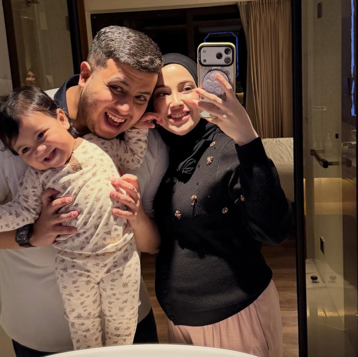 <p>Miskah membagikan potret kebersamaan bersama suami dan anak pertamanya dalam sebuah foto di depan cermin. Potret kehangatan begitu terasa saat Yislam penuh semangat menggendong Aisha yang tampak aktif berdiri di dekat area cuci tangan.(Foto:@aishajaidiii)</p>