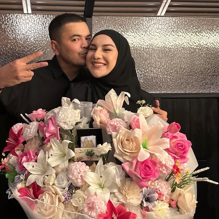 <p>Perempuan 30 tahun ini tampak tersenyum semringah saat diberi buket bunga berukuran besar dari suami. Sementara Haldy Sabri penuh kasih sayang memberikan kecupan hangat di pipi sang istri sambil berpose mesra di balik buket bunga.(Foto:@_irishbella_)</p>