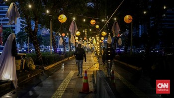 Sejumlah pejalan kaki melintasi instalasi bertema Halloween di sepanjang trotoar kawasan Sudirman, Jakarta, Rabu (21/10/2026). (CNN Indonesia/Febria Adha L)