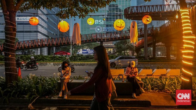 Sejumlah pejalan kaki melintasi instalasi bertema Halloween di sepanjang trotoar kawasan Sudirman, Jakarta, Rabu (21/10/2026). (CNN Indonesia/Febria Adha L)