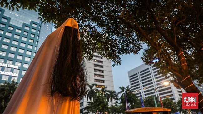 Sejumlah pejalan kaki melintasi instalasi bertema Halloween di sepanjang trotoar kawasan Sudirman, Jakarta, Rabu (21/10/2026). (CNN Indonesia/Febria Adha L)