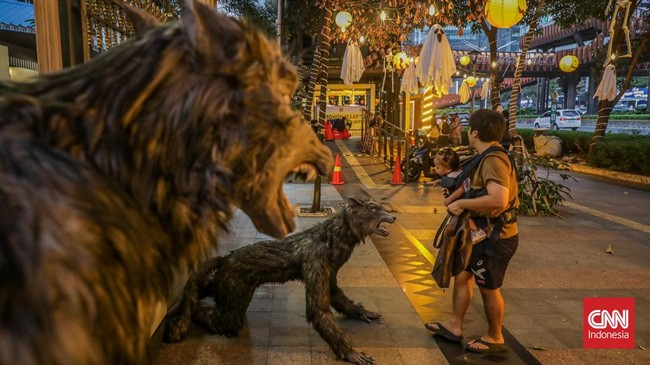 Sejumlah pejalan kaki melintasi instalasi bertema Halloween di sepanjang trotoar kawasan Sudirman, Jakarta, Rabu (21/10/2026). (CNN Indonesia/Febria Adha L)