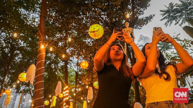 Sejumlah pejalan kaki melintasi instalasi bertema Halloween di sepanjang trotoar kawasan Sudirman, Jakarta, Rabu (21/10/2026). (CNN Indonesia/Febria Adha L)