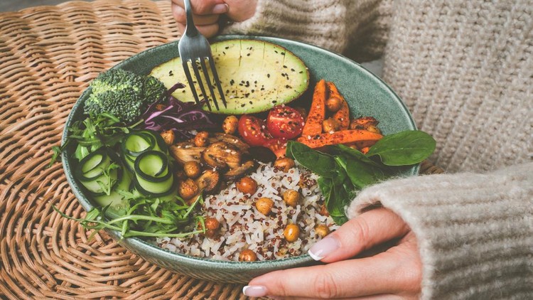 Woman eating healthy buddha bowl&period; Buddha bowl with rice&comma; quinoa&comma; avocado and vegetables&period; High quality photo