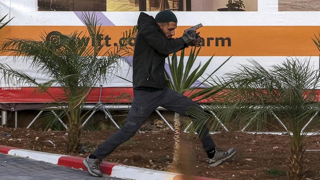 One of two armed Palestinian men runs during a fire exchange with Israeli forces at the northern checkpoint of Hebron in the Israeli-occupied West Bank on October 23, 2026. Israeli troops on October 23 shot dead two suspected Palestinian assailants i