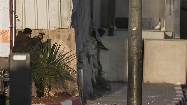 EDITORS NOTE: Graphic content / One of two armed Palestinian men (L) points his handgun while exchanging fire with Israeli forces at the northern checkpoint of Hebron, in the Israeli-occupied West Bank, on October 23, 2026. Israeli troops on October