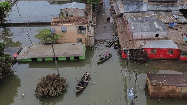 A drone view shows people traveling by boats through a flooded neighborhood after heavy rains, in Ciudad del Este, Paraguay, October 21, 2026. REUTERS/Cesar Olmedo