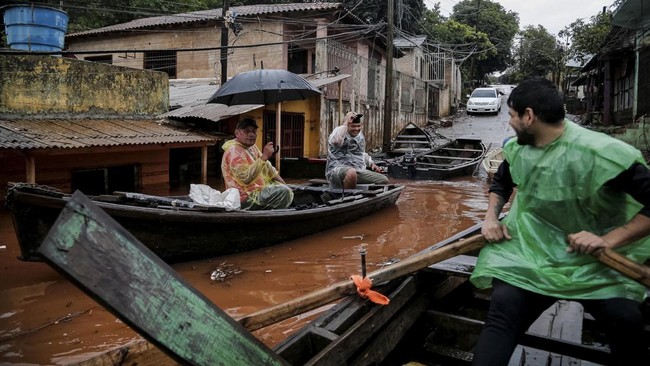 People travel by boat through a flooded neighborhood after heavy rains, in Ciudad del Este, Paraguay, October 22, 2026. REUTERS/Cesar Olmedo