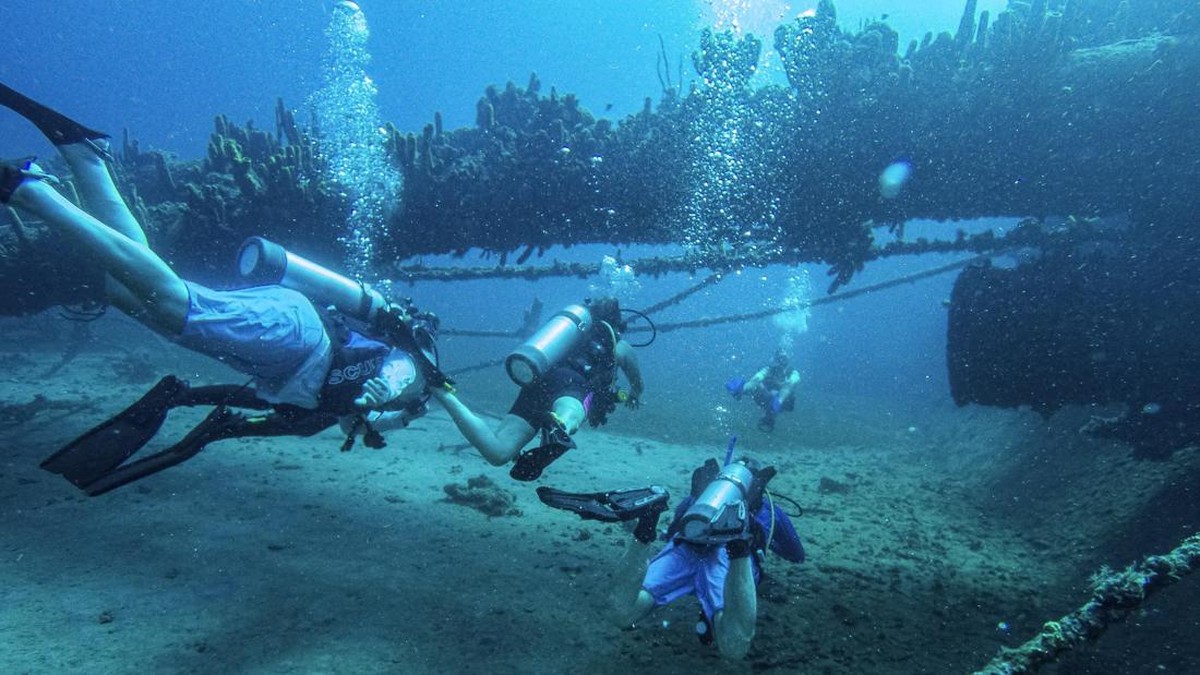 Scuba divers swim by the World War II shipwreck of German SS Antilla in the southern Caribbean Sea, off Malmok Bay in the western coast of Aruba, on October 22, 2026. (Photo by Joseph Prezioso / AFP)