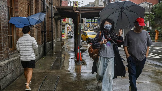 Pedestrians walk along a street as Typhoon Champi approaches Taiwan, in Keelung, Taiwan, October 23, 2026. REUTERS/Ann Wang     TPX IMAGES OF THE DAY