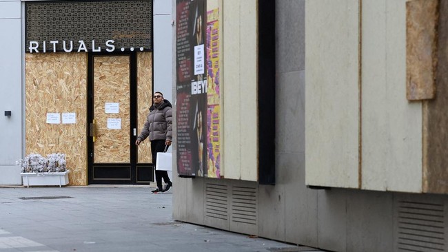 A man walks past stores protected with wooden panels in Lyon, ahead of nationwide protests against the cost of living and rising fuel prices in France, October 23, 2026. REUTERS/Lisi Niesner