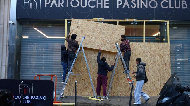 Workers install wooden panels to protect the windows of the gaming club Partouche Pasino Club in Paris ahead of nationwide protests called by the
