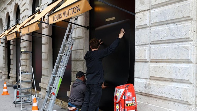 Workers install panels to protect the storefront windows of a Louis Vuitton store in Lyon, ahead of nationwide protests against the cost of living and rising fuel prices in France, October 23, 2026. REUTERS/Lisi Niesner