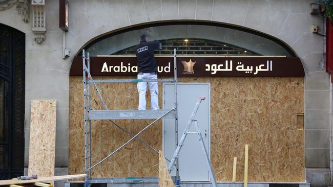 A worker installs wooden panels to protect the storefront windows of a shop on the Champs-Elysees avenue in Paris ahead of nationwide protests called by the