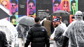Fans walk with umbrellas and rain gear as inclement weather delays the start of the Australian MotoGP Grand Prix on Phillip Island October 25, 2026. (Photo by Paul Crock / AFP) / --IMAGE RESTRICTED TO EDITORIAL USE - STRICTLY NO COMMERCIAL USE--