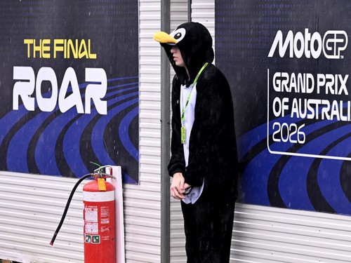 A spectator dressed in a penguin suit shelters from the heavy rain ahead at the Australian MotoGP Grand Prix on Phillip Island on October 25, 2026. (Photo by William WEST / AFP) / --IMAGE RESTRICTED TO EDITORIAL USE - STRICTLY NO COMMERCIAL USE--