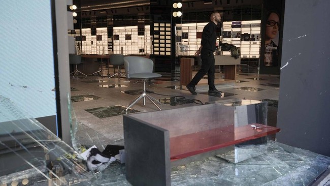 An employee inspects an optician's shop looted the previous night during riots, in Barcelona on October 25, 2026. Police made 128 arrests overnight in Barcelona for acts of "vandalism", damage to public property" and "looting", the regional Catalan p