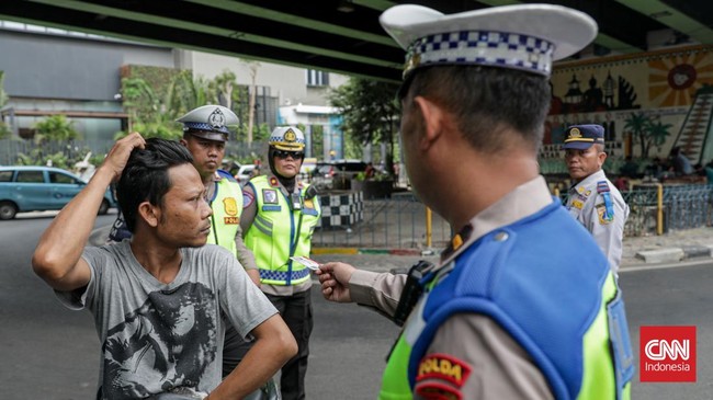 Sejumlah petugas kepolisian menilang pengendara sepeda motor dalam Operasi Patuh Jaya 2026 di Jalan Kemanggisan Raya, Slipi, Jakarta, Senin (26/10/2026). (CNN Indonesia/Febria Adha L)