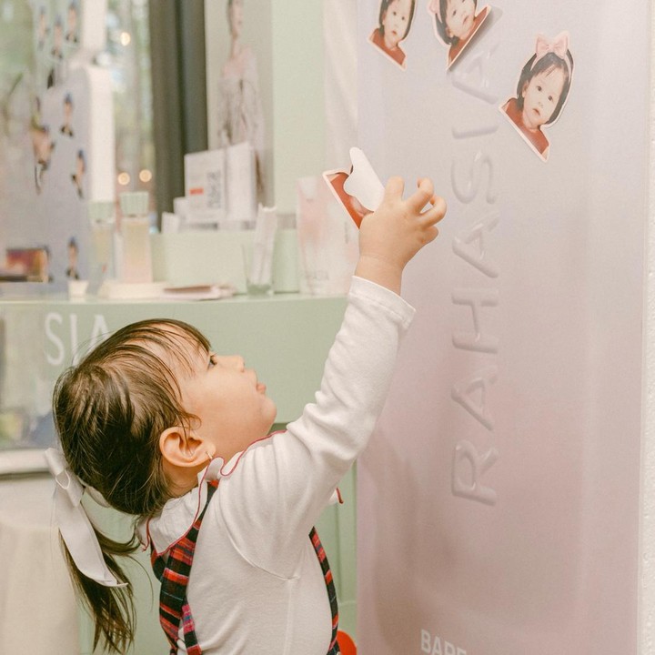 <p>Putri sulung mereka Kyarra Arunika Hasibuan juga tampak menggemaskan bermain dan menempelkan stiker di papan dekorasi acara. Kyarra juga ikut berdoa bersama kedua orangtuanya di gender reveal.(Foto:@jscmila)</p>
