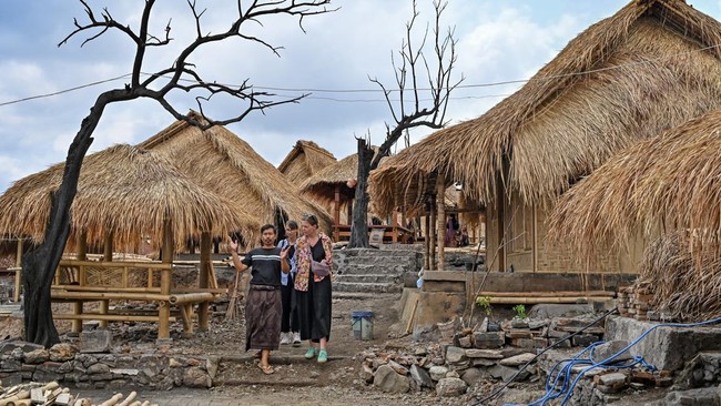 Pemandu wisata berbincang dengan wisatawan asing saat  berkunjung ke Desa wisata adat Sade, Rembitan, Kecamatan Pujut, Praya, Lombok Tengah, NTB, Rabu (28/10/2026). Dua bulan pasca kebakaran yang melanda Desa wisata Adat Sade sejumlah wisatawan mulai