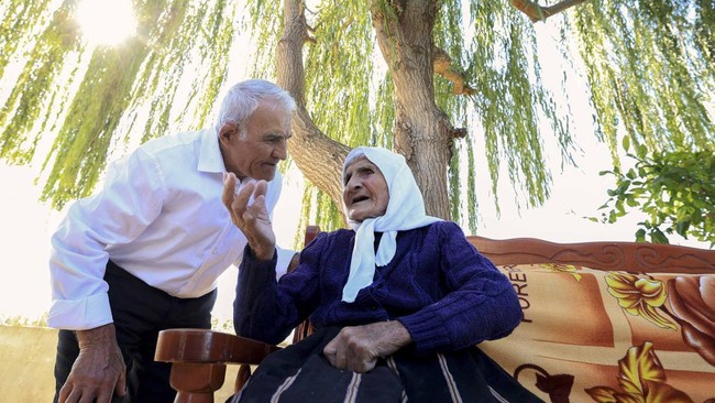 The 117-year-old Qamile Marra speaks with her son Hysen Marra, 80, in the garden of her home in the village of Ferras, near Kucove, some 80 kilometres from the Albanian capital Tirana on October 3, 2026. At 117, Qamile Marra's priority isn't proving