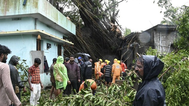 National Disaster Response Force (NDRF) personnel gather near houses damaged by uprooted trees after cyclone Arnab's landfall in Yanam, in India's Puducherry on October 28, 2026. At least three people were killed as ferocious winds and torrential rai