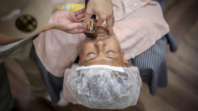 This photo taken on August 27, 2026 shows Tekisasu, an active yakuza gangster allied to a major clan, having his beard trimmed at a barbershop in Tokyo. Japan's yakuza operate an organised crime empire worth billions of dollars and have long dominate
