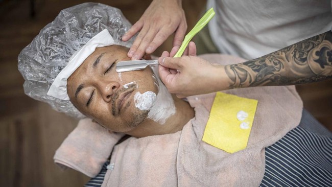 This photo taken on August 27, 2026 shows Tekisasu, an active yakuza gangster allied to a major clan, having his beard shaved at a barbershop in Tokyo. Japan's yakuza operate an organised crime empire worth billions of dollars and have long dominated